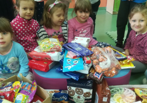 dzieci siedzą przy słodyczach, które przyniosły